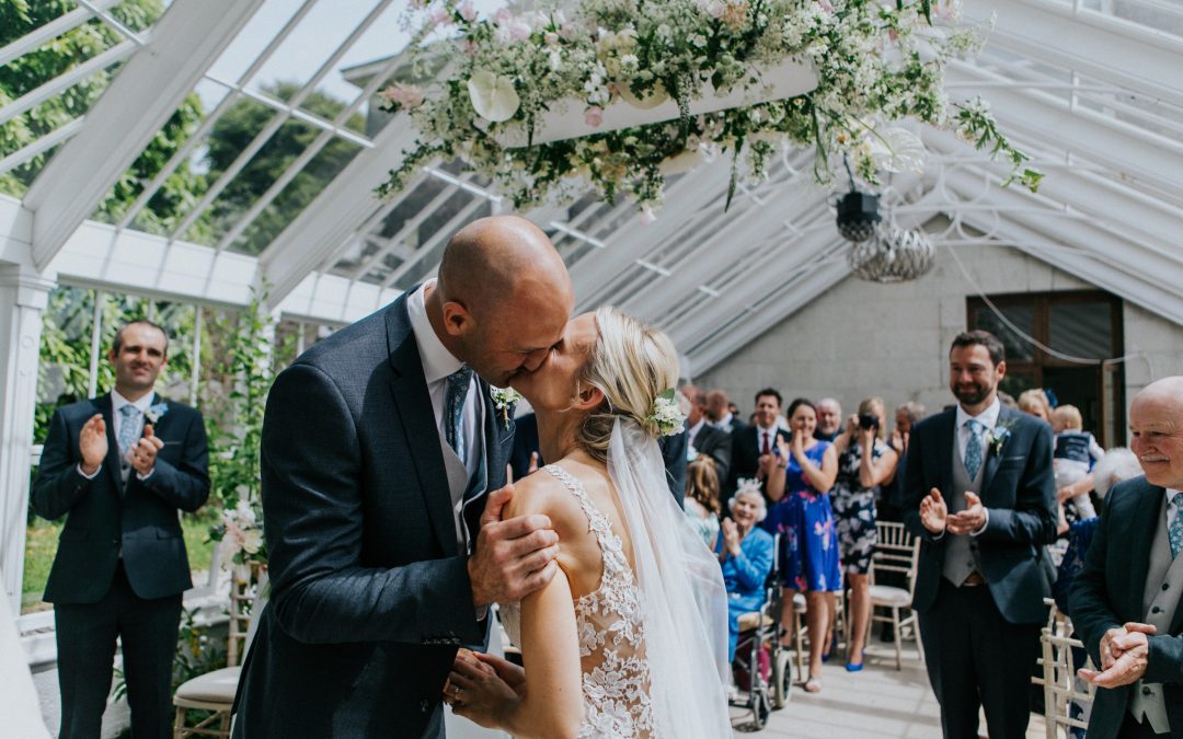 Intimate weddings at Burncoose House, bride and groom say 'I do' in conservatory filled with flowers